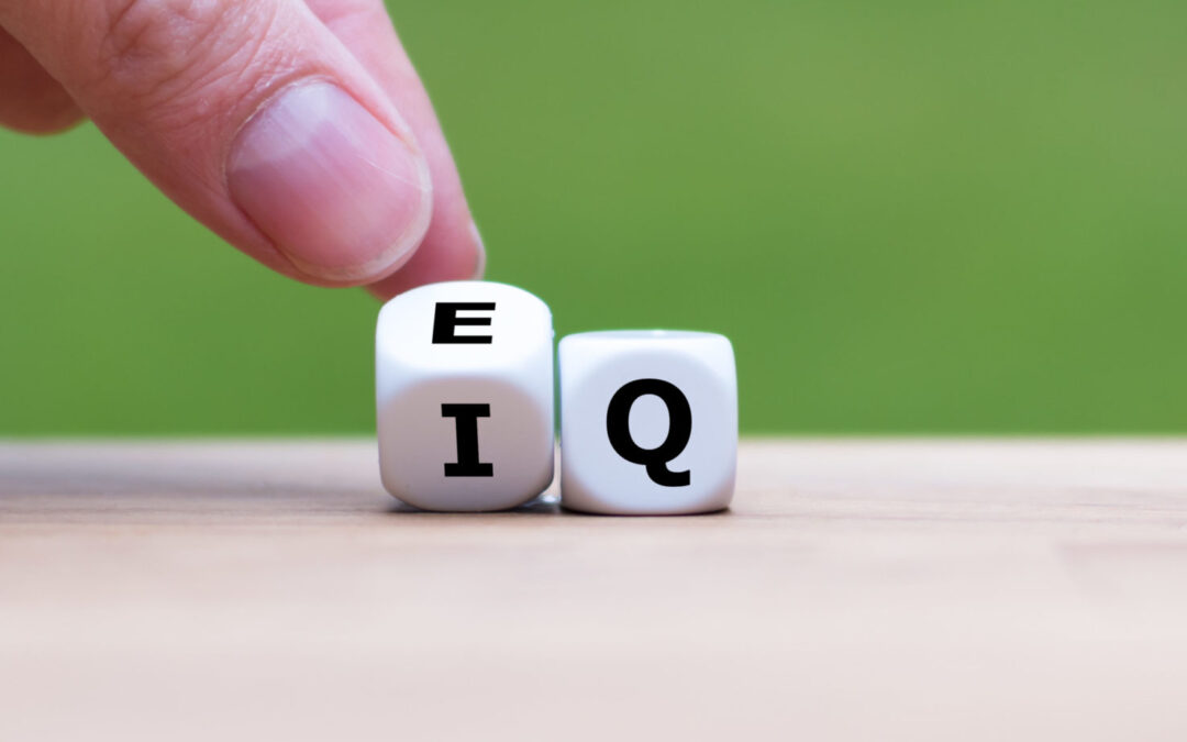 Hand turns a dice and changes the expression “IQ” (Intelligence Quotient) to “EQ” (Emotional Intelligence/Quotient).